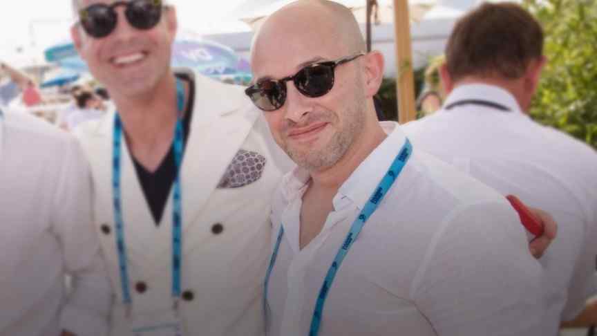 Eyal Eran in white shirt and sunglasses smiling, more people in white shirts in the background