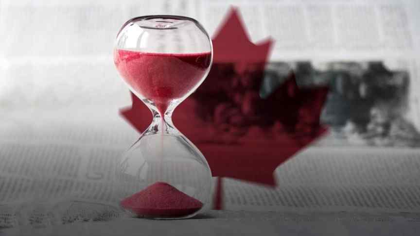 sand watch with red sand on background of newspaper with Canada's red maple leaf