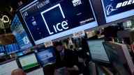 Intercontinental exchange room, people sitting at computers, big screens showing ICE