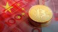 a stack of gold bitcoins laid on Yuan bills