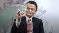 Jack Ma in suit, red tie, raisedhand, a picture of the globe in the background