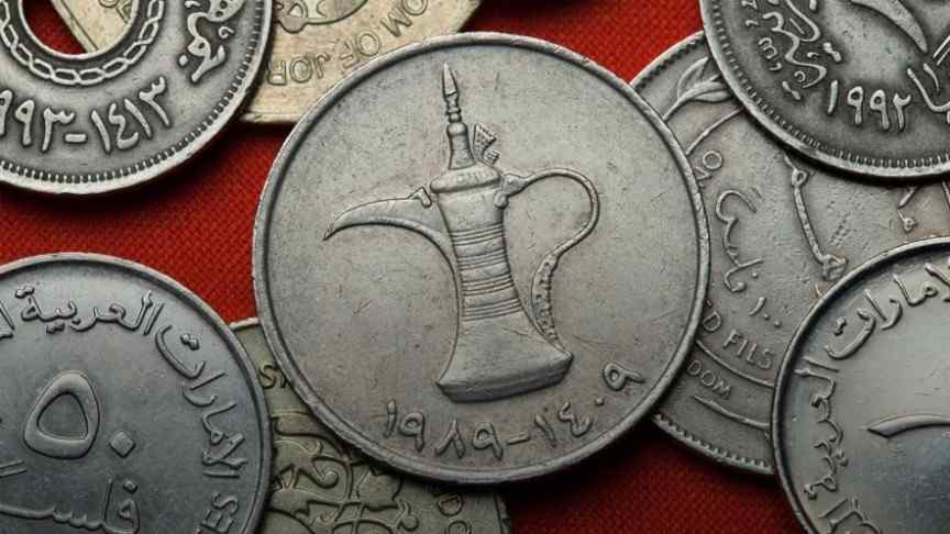 old silver coins with Arabic writings lying on red surface