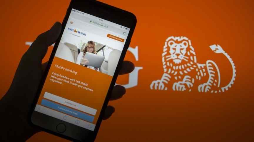 hand holding phone showing ING bank website. ING logo in the background
