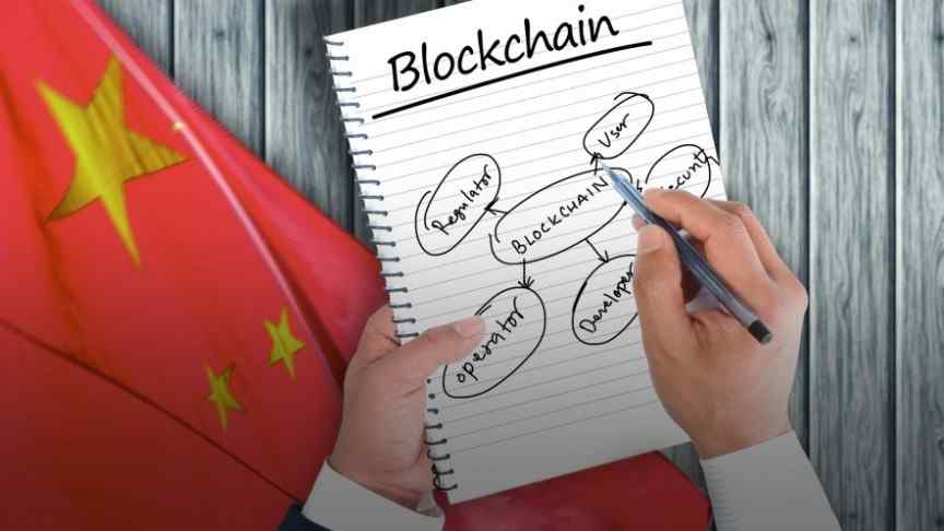 Chinese flag, wooden table, hand writing in notebook that says Blockchain