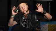 Brock Pierce holding arms up, holding phone, wearing ear piece