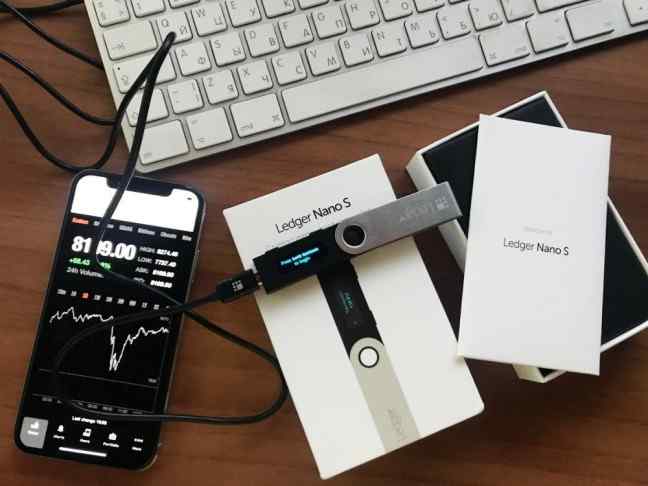 Ledger Nano S Hardware Wallet, a mobile phone and part of a computer keyboard