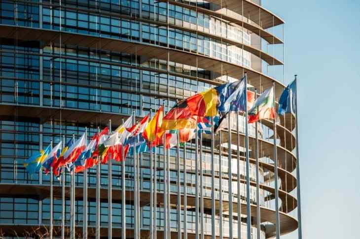 Worldwide flags waving in the wind in front of a modern building