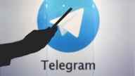 Hand pointing to the Telegram logo