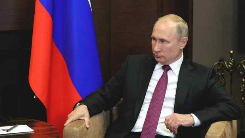 Vladimir Putin next to Russian Flag; contemplative look illustrating Russia’s attitude toward cryptocurrency regulation.