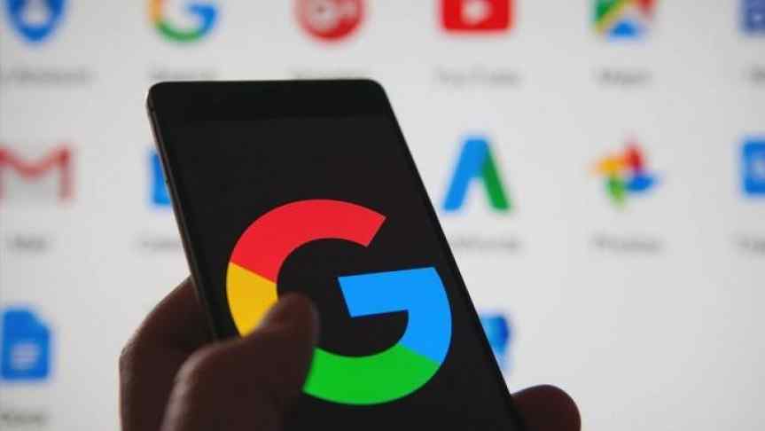 Google logo displayed on a phone, hold in front of a computer