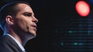Roger Ver seen from his right profile, wearing a suit looking into distance. Black background and red spotlight pointing at Ver.