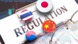 Regulation sign on clipboard, Thailand, China, Japan and South Korea flags on pins, glasses lying on paper