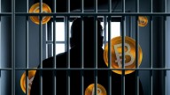 man behind bars, several Bitcoin logos in background