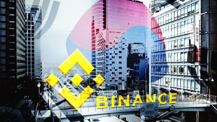 Binance name and logo in yellow on background of Korean street in black and white and blurry Korean flag in blue and red