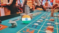 roulette table with chips, people around and a chip showing India's flag