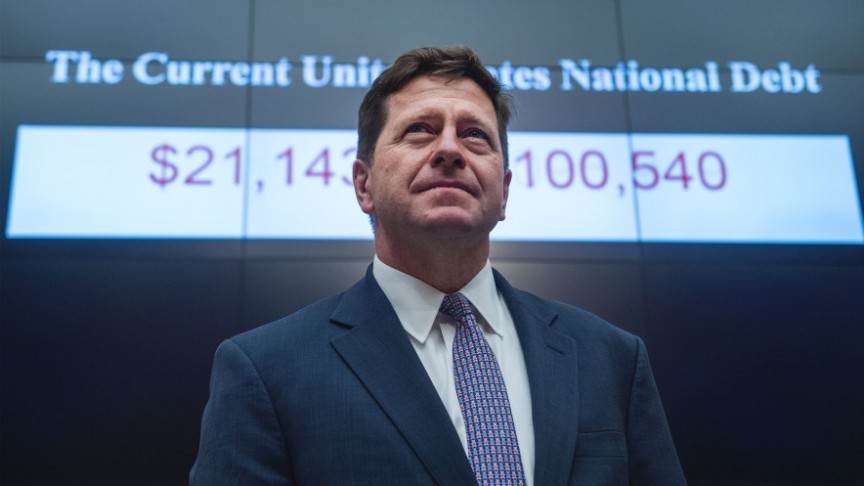 Clayton in suit standing on background of presentation