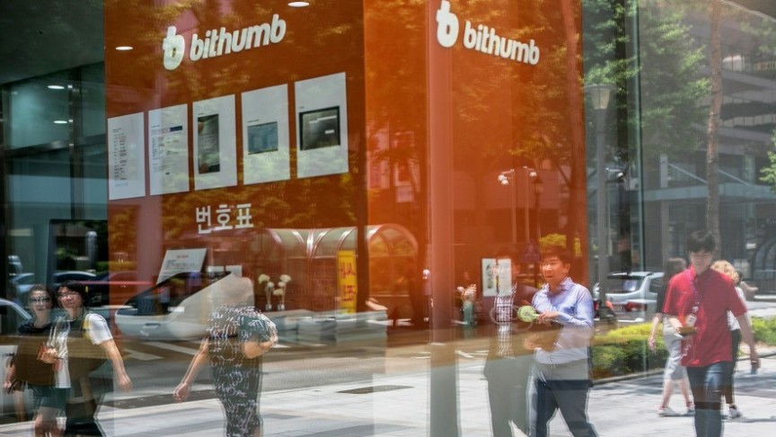 opque people walking in street in front of orange Bithumb building