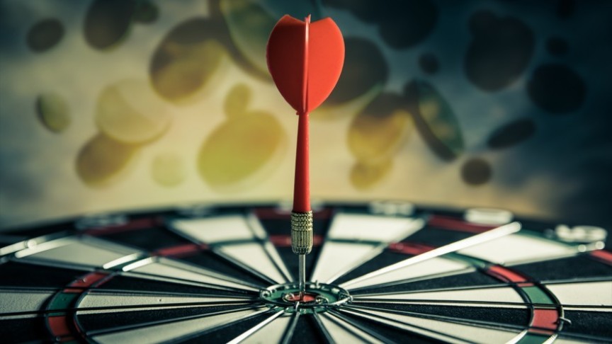 a red dart stuck in the center of a dartboard, gold coins in the background