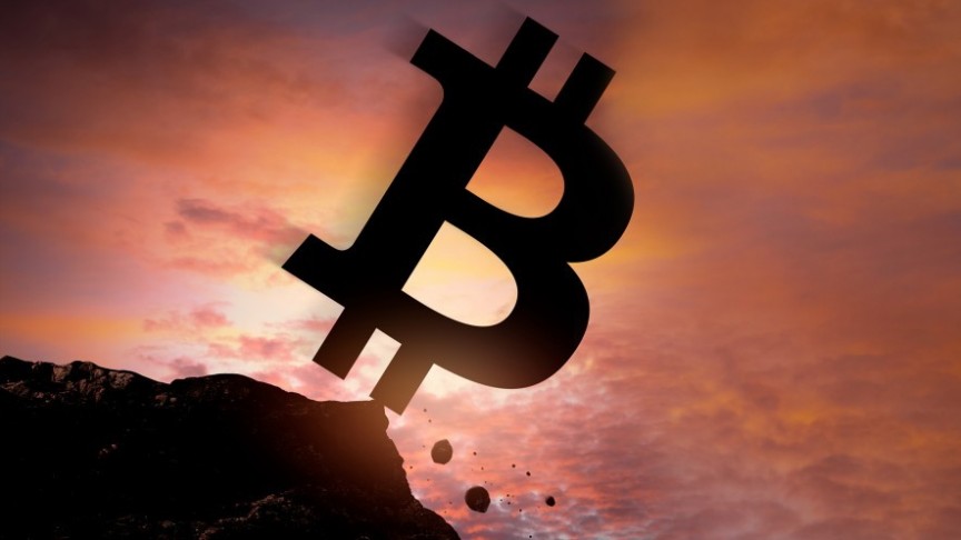 bitcoin logo falling off cliff on sunset background