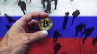 hand holding Bitcoin above train station with people walking, Russian flag colors on floor
