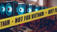 police yellow tape reading 'NOT FOR VIETNAM surrounding lighted mining rigs