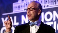 Jeffrey Tucker in suit and bowtie and glasses, pointing up 